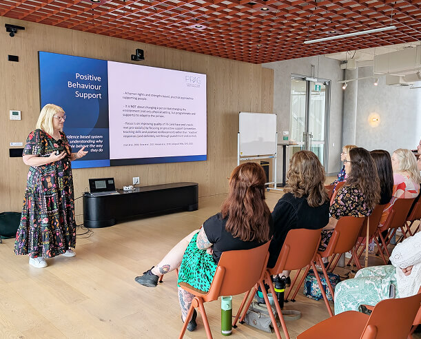 A woman standing before a crowd of seated people